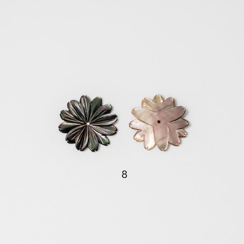 Puede incluir: Dos objetos decorativos con forma de flor. Uno es gris oscuro con brillo met&aacute;lico, y el otro es rosa claro con acabado nacarado. Ambos tienen un agujero central. El n&uacute;mero "8" est&aacute; impreso en negro debajo.