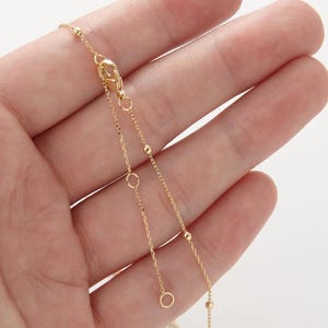 May include: A gold chain necklace with small round beads. The chain is delicate and has a lobster clasp.