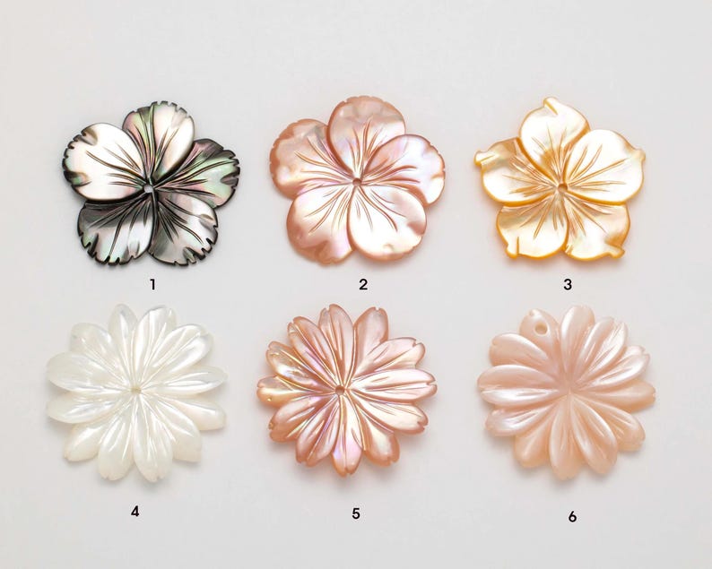 Puede incluir: Seis colgantes con forma de flor en varios colores. Los colgantes est&aacute;n hechos de n&aacute;car. Los colores incluyen negro iridiscente, melocot&oacute;n, dorado y blanco. Cada colgante tiene un dise&ntilde;o de p&eacute;talo diferente, algunos con un agujero para ensartar.
