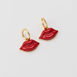 May include: A pair of gold hoop earrings with red enamel lips dangling from the hoops.