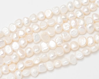 May include: Close-up of several strands of creamy white, irregularly shaped freshwater pearls. The pearls have a lustrous sheen and vary in size and shape, creating a natural, organic look. The pearls are strung together, ready for jewelry making.