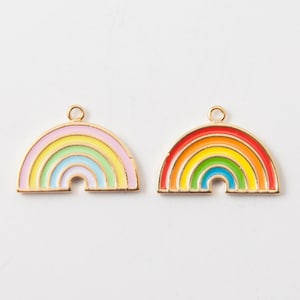 May include: Two gold-tone rainbow charms with enamel paint. The rainbow charm on the left has pink, yellow, green, and blue stripes. The rainbow charm on the right has red, orange, yellow, green, and blue stripes.