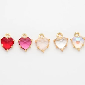 May include: Five gold heart-shaped charms with different colored glass inserts. The charms are red, pink, clear, and iridescent.