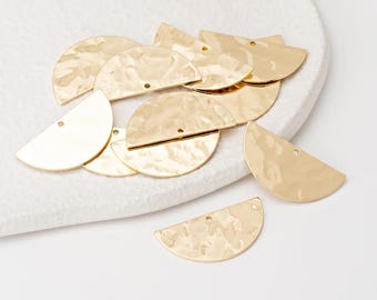 May include: A selection of gold-coloured, half-circle metal charms with a hammered texture. Each charm has a small hole for attaching to jewellery. The charms are arranged on a white surface.