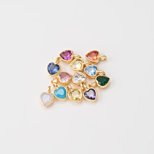 May include: A collection of gold heart-shaped charms with various colored gemstones, including turquoise, pink, red, blue, green, and clear.