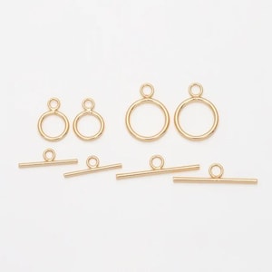 May include: Gold-toned metal toggle clasps and jump rings in various sizes. The clasps have a straight bar and a round ring. The jump rings are round with a small opening.