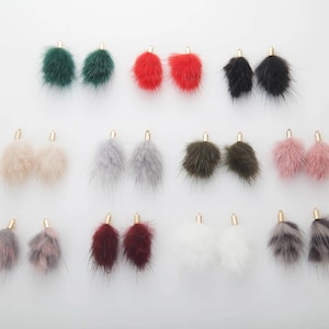 May include: A collection of fluffy, colorful earrings in various shades, including green, red, black, beige, gray, olive, pink, and white. Each earring features a gold-colored metal top. The earrings are designed for a stylish accessory.