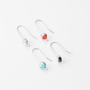 Könnte beinhalten: Vier Paar silberfarbene Hakenohrringe. Jeder Ohrring hat eine kleine, runde Perle in Rot, Schwarz, Türkis oder Silber. Die Ohrringe sind auf weißem Hintergrund dargestellt.