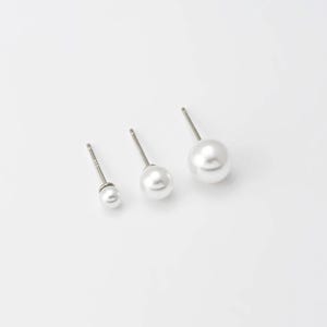 Op de afbeelding: Drie paar parel oorbelletjes in verschillende maten. De oorbelletjes zijn zilverkleurig met witte parels.
