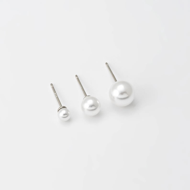 Op de afbeelding: Drie paar parel oorbelletjes in verschillende maten. De oorbelletjes zijn zilverkleurig met witte parels.