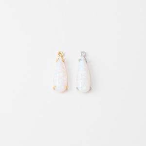 May include: Two teardrop-shaped pendants featuring iridescent white stones. One pendant is set in a gold-toned metal frame with a small loop at the top, and the other is set in a silver-toned metal frame with a matching loop at the top.