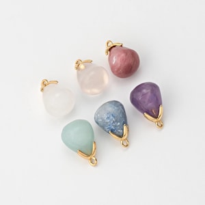 Puede incluir: Seis colgantes de piedras preciosas diferentes con engarces de metal dorado. Las piedras preciosas son de varias formas y colores, incluyendo rosa, transparente, morado, azul y verde.