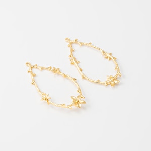 May include: Two gold-tone metal earring blanks in the shape of a teardrop with a floral design. The blanks have a loop at the top for attaching earrings.