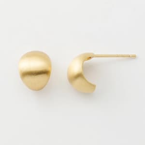 May include: A pair of gold-coloured earrings. One is a rounded stud, the other a small, curved hoop. The earrings have a matte finish against a white background.