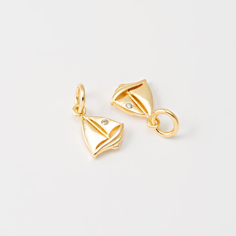 May include: Two gold sailboat charms with a clear rhinestone on each. The charms have a loop for attaching to a bracelet or necklace.