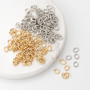 May include: A pile of gold and silver jump rings. The jump rings are small and round, and they are perfect for jewelry making.
