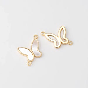 May include: Two gold-tone butterfly charms with white mother-of-pearl accents. Each charm has a loop on either side for attaching to jewelry.