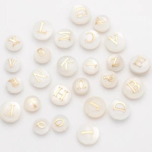 May include: White round beads with gold letters spelling out the alphabet.