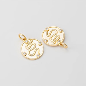 Puede incluir: Dos dijes de color dorado con un diseño de serpiente y detalles de cristal transparente.