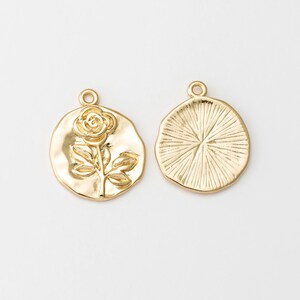 May include: Two gold-tone metal charms, one with a raised rose design and the other with a textured circular design.