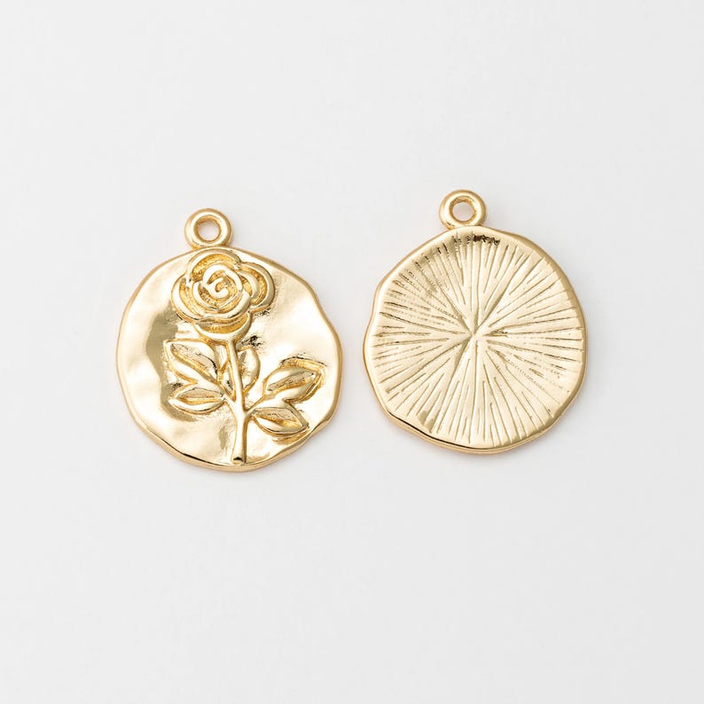 May include: Two gold-tone metal charms, one with a raised rose design and the other with a textured circular design.
