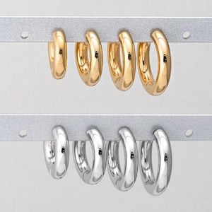 May include: A set of six hoop earrings, three in gold and three in silver. The earrings are displayed on a silver bar.