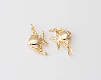 May include: Two gold-colored fish pendants with a shiny finish. Each fish has a detailed design with fins and a loop for hanging. Small, clear stones are set along the fins, adding sparkle. The pendants are set against a plain white background.