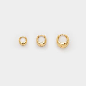 May include: Three gold-coloured hoop earrings of varying sizes are displayed against a white background. The earrings have a smooth, rounded design with a hinged closure. The smallest earring is approximately 1.3 cm in diameter, the medium is 1.9 cm, and the largest is 2.5 cm.