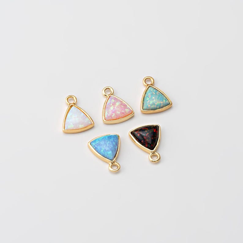 May include: Five gold triangle charms with different colored opal stones. The stones are white, pink, blue, light blue, and black.