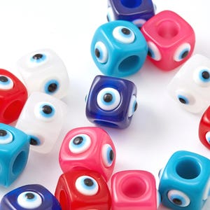 Könnte beinhalten: Sortiment an bunten Plastikwürfelperlen mit einem bösen Augen-Design. Die Perlen sind in den Farben Blau, Rot, Pink und Weiß.