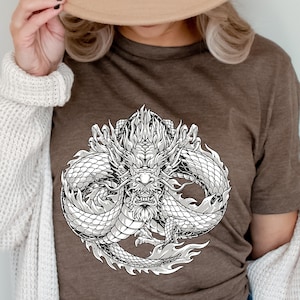 Puede incluir: Una camiseta marrón con un gráfico blanco de un dragón detallado con la boca abierta y los colmillos a la vista.
