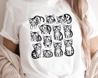 May include: White t-shirt featuring a grid of sixteen black and white kitten illustrations. Each kitten has a unique pose, with striped markings and expressive eyes. The shirt is made of a soft, comfortable material.