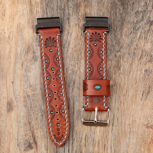 May include: Two brown leather watch bands with black hardware and silver buckles. The bands feature turquoise accents and decorative stitching. The bands have a Southwestern design with floral and geometric patterns.