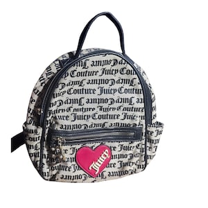 May include: A small, beige backpack with a black handle and straps. The bag is covered in a repeating pattern of the words "Juicy Couture" in black script. A pink heart-shaped patch with "Juicy" in white is on the front.