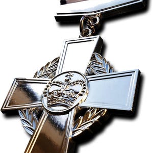 May include: A shiny silver medal with a cross design, featuring a central emblem of a crown. The medal is attached to a ribbon with red, white, and blue stripes. The medal has a polished finish and is set against a white background.