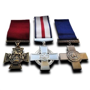 May include: Three military medals with cross designs and colorful ribbons. The medals are in bronze, silver, and gold tones. The ribbons are red, white and red, and blue. The medals are for valor and gallantry.