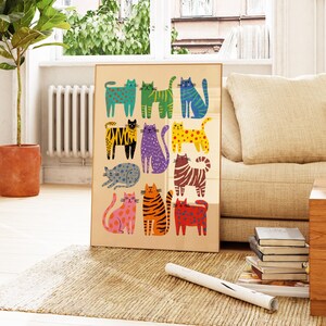 May include: A framed art print featuring a collection of stylized cats in various colors and patterns. The cats are arranged in rows on a beige background, with a gold frame. The artwork is displayed in a living room setting.