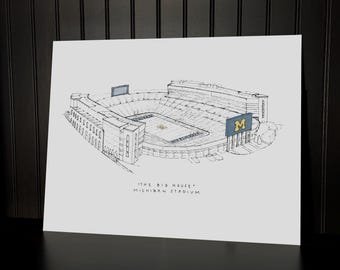 Puede incluir: Un boceto en blanco y negro del estadio de Michigan, también conocido como "The Big House". La obra de arte representa el exterior del estadio, incluyendo los asientos, los marcadores y el campo. El nombre y el apodo del estadio están escritos debajo.