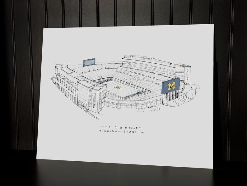Puede incluir: Un boceto en blanco y negro del estadio de Michigan, tambi&eacute;n conocido como "The Big House". La obra de arte representa el exterior del estadio, incluyendo los asientos, los marcadores y el campo. El nombre y el apodo del estadio est&aacute;n escritos debajo.