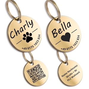 Könnte beinhalten: Zwei goldfarbene Hunde-ID-Marken. Eine Marke trägt den Namen "Charly" mit einem Pfotenabdruck, die andere "Bella" mit einem Herz. Beide Marken enthalten eine Telefonnummer. Zusätzliche kleine Marken haben einen QR-Code und Informationen zum Besitzer.