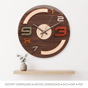 May include: A circular wall clock with a dark wood grain finish, featuring a central light-colored circular dial and three thin metal hands. The clock face displays raised, multi-colored numerals and curved segments in shades of tan, green, and red.
