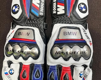 Puede incluir: Un par de guantes de moto negros, blancos, rojos y azules. Los guantes presentan el logotipo de BMW, el texto "BMW S1000R" y la palabra "Motorrad". Los guantes tienen un protector de nudillos y son de cuero.
