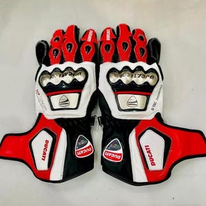 May include: A pair of black, white, and red motorcycle gloves with the Ducati Corse logo. The gloves have a D-Tec engineered design and are made of leather.