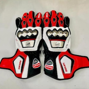 May include: A pair of black, white, and red motorcycle gloves with the Ducati Corse logo. The gloves have a D-Tec engineered design and are made of leather.