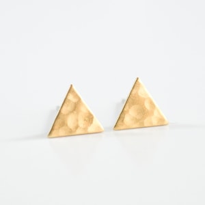 May include: A pair of gold triangle stud earrings with a hammered texture.