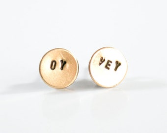 May include: A pair of gold-toned earrings with the words "OY" and "VEY" stamped on them.