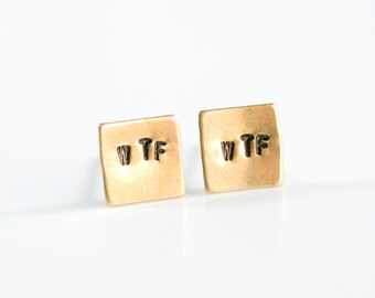 May include: A pair of gold square-shaped earrings with the letters "WTF" stamped on each earring.