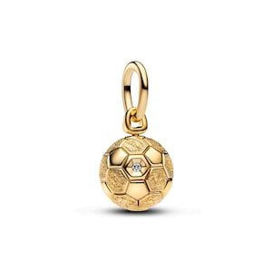 Könnte beinhalten: Ein goldfarbener Fußball-Charm mit einem kleinen, klaren Edelstein in der Mitte. Der Charm ist an einer passenden Goldschlaufe aufgehängt. Der Fußball hat eine strukturierte Oberfläche mit sechseckigen Feldern.