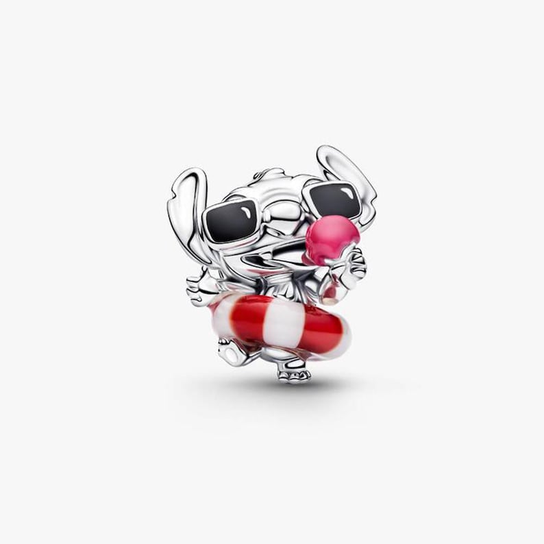 May include: A silver charm featuring the character Stitch from Lilo & Stitch. Stitch wears sunglasses and holds a pink ice cream cone. He is also wearing a red and white striped inflatable ring. The charm is detailed and has a polished finish.