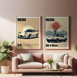 Op de afbeelding: Twee ingelijste Mazda auto kunstprints. De linkerprint toont een witte sportwagen met de tekst "R-X7" eronder. De rechterprint toont een zwarte cabriolet met de tekst "MX-5 Miata". Beide prints hebben een beige achtergrond en worden boven een roze bank weergegeven.